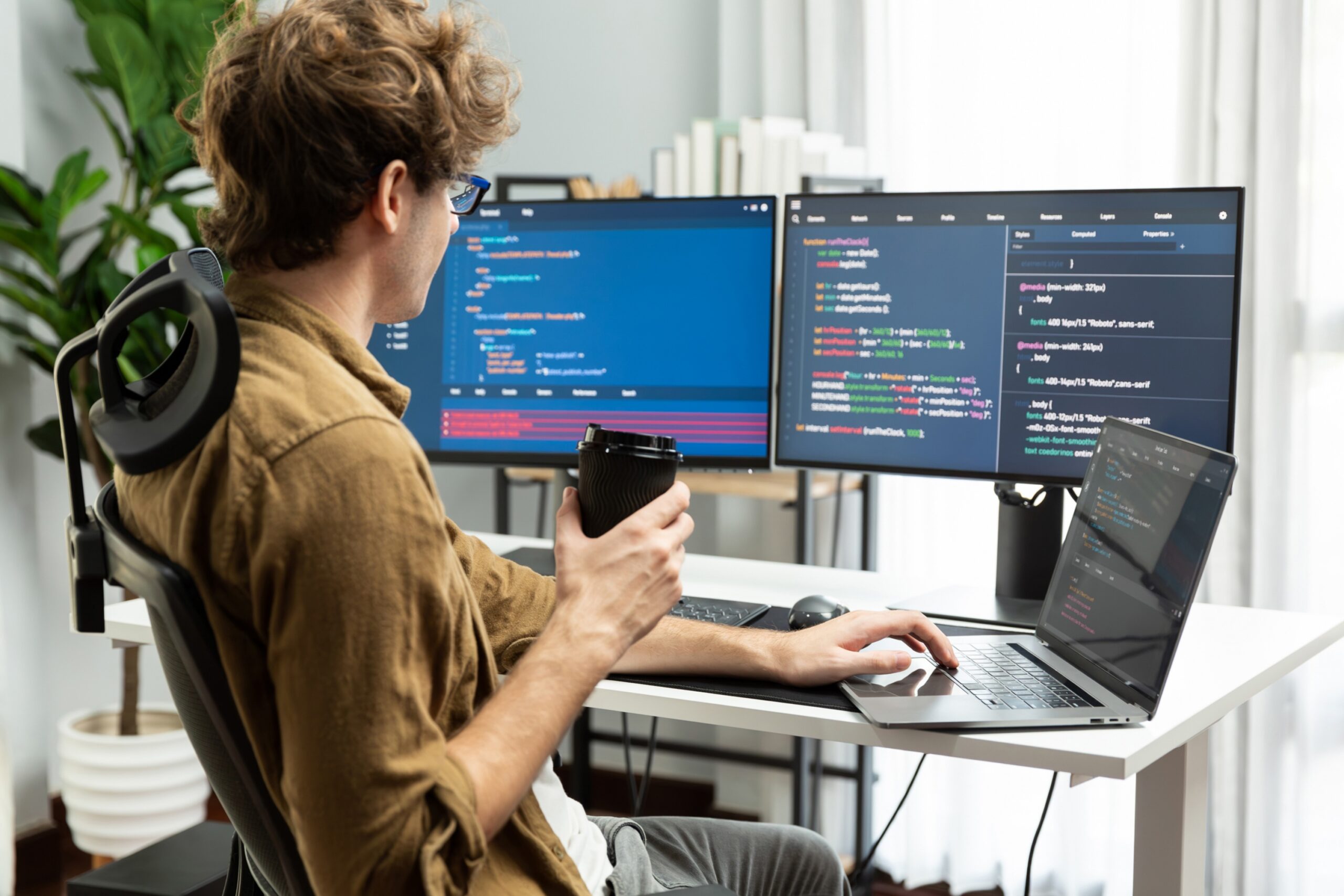 Full-Stack developer holding coffee cup with looking online software on pc at modern office on coding application screens